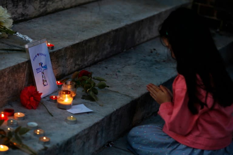 A girl prays in front of city hall in the Normandy city of Saint-Etienne du Rouvray on July 26, 2016 in tribute to the priest killed in the city's church