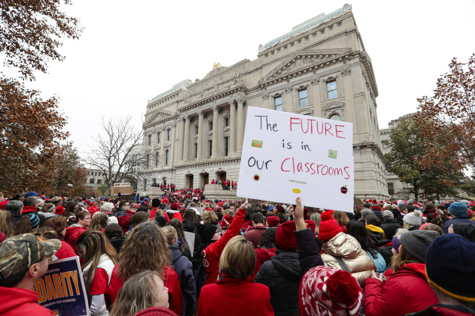 Thousands of Indiana teachers wearing red surround the Statehouse in Indianapolis, Tuesday, Nov. 19, 2019 for a rally calling for further increasing teacher pay in the biggest such protest in the state amid a wave of educator activism across the country. Teacher unions says about half of Indiana's nearly 300 school districts are closed while their teachers attend Tuesday's rally while legislators gather for 2020 session organization meetings.(AP Photo/Michael Conroy)