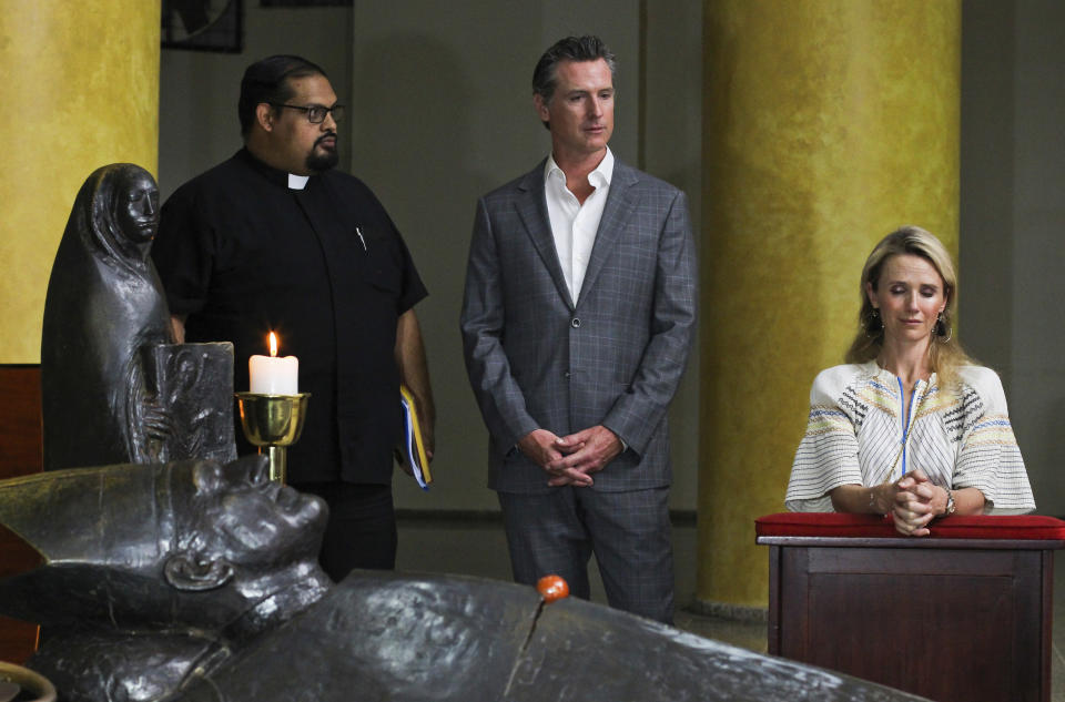 California Gov. Gavin Newsom and his wife, Jennifer Siebel Newsom, visit the tomb of Archbishop Oscar Romero at Metropolitan Cathedral in San Salvador, El Salvador, Sunday, April 7, 2019. Father Francisco Villalobos stands at left. Newsom visited the tomb of Archbishop Romero, the Salvadoran priest assassinated in 1980 due to his advocacy for human rights and the poor. (AP Photo/Salvador Melendez, Pool)