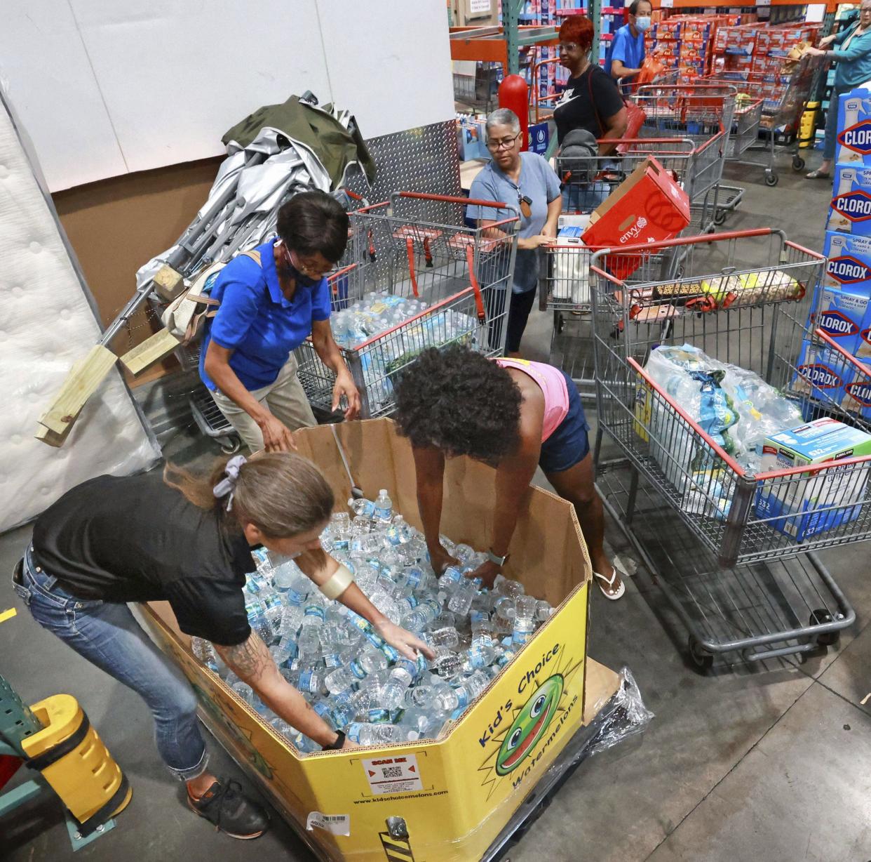 Shoppers at the Costco store in Altamonte Springs, Fla. grab bottles of water from the last pallet in stock on Monday, Sept. 26, 2022, as Central Floridians prepare for the impact of Hurricane Ian.