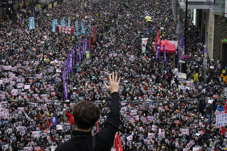 in this Jan. 1, 2020, photo, a protester shows a five demands gesture as Hong Kong people participate in their annual pro-democracy march to insist their five demands be matched by the government in Hong Kong. The city's often-tumultuous street protests had already slowed in the past two months. Now they have ground to an almost complete halt as attention focuses on how to avoid a recurrence of the SARS pandemic, which killed about 300 people in Hong Kong in 2002-03. (AP Photo/Vincent Yu)