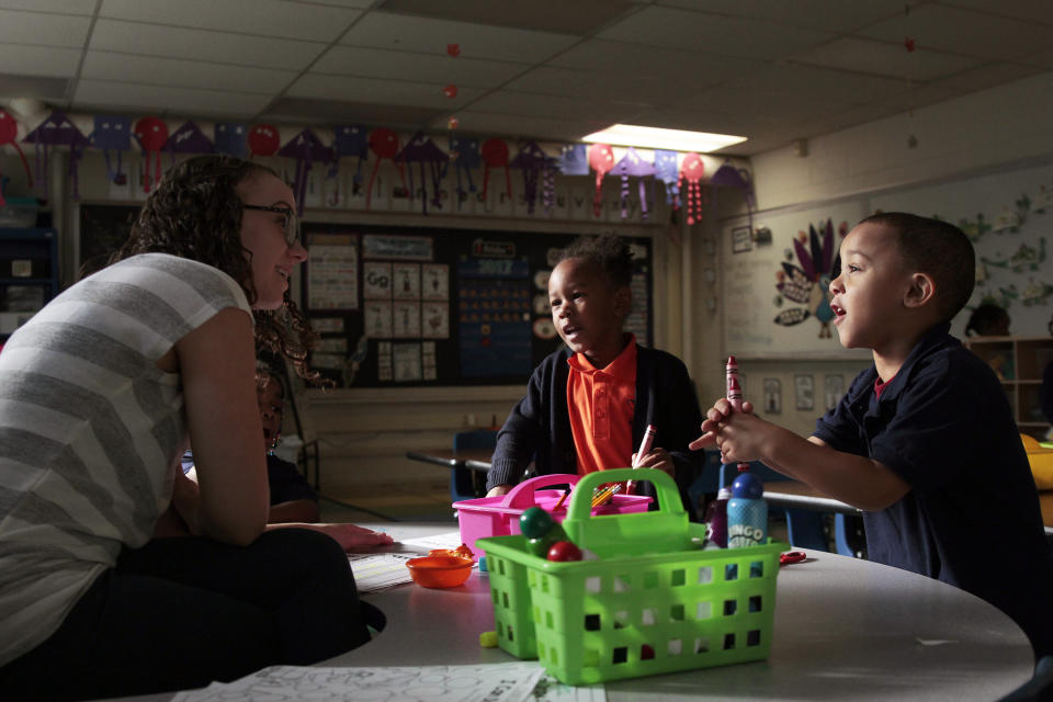 In this photo taken Oct. 20, 2017, K-4 students Devon Daniels, left, and Charlie Webb talk to teacher Dana Chrzanowski at Milwaukee Math and Science Academy, a charter school in Milwaukee. Charters are vastly over-represented among schools where minorities study in the most extreme racial isolation, according to an analysis of enrollment data nationwide by The Associated Press. As of school year 2014-2015, more than 1 in 7 charter schools had minority enrollment of at least 99 percent, and the number has been rising steadily.  (AP Photo/Carrie Antlfinger)