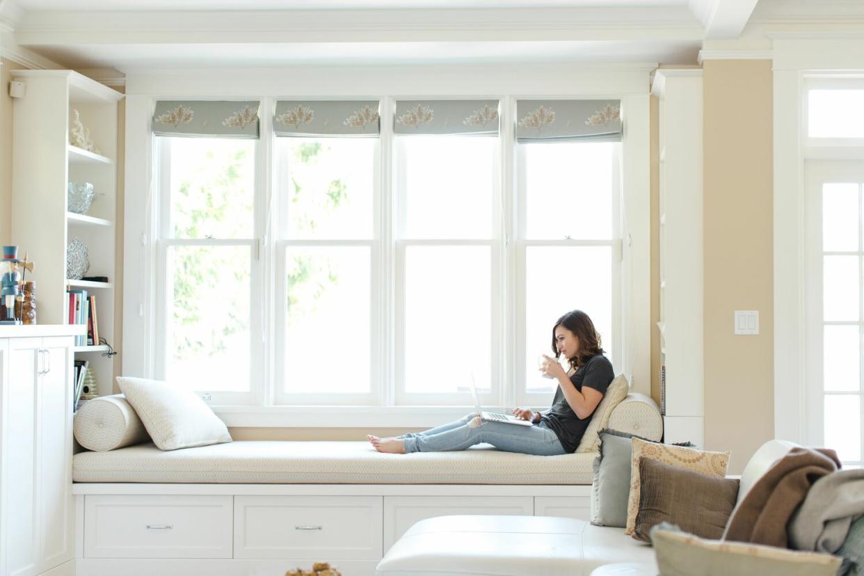 woman on computer in front of big windows