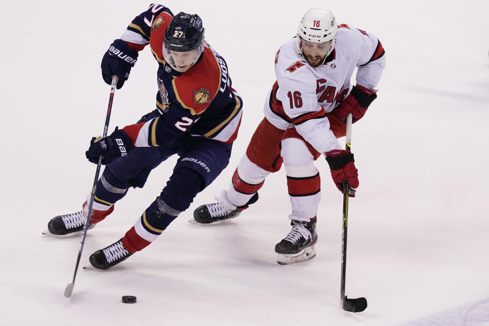 Florida Panthers center Eetu Luostarinen (27) and Carolina Hurricanes center Vincent Trocheck (16) go after the puck during overtime at an NHL hockey game, Saturday, Feb. 27, 2021, in Sunrise, Fla. The Hurricanes defeated the Panthers 4-3. (AP Photo/Marta Lavandier)