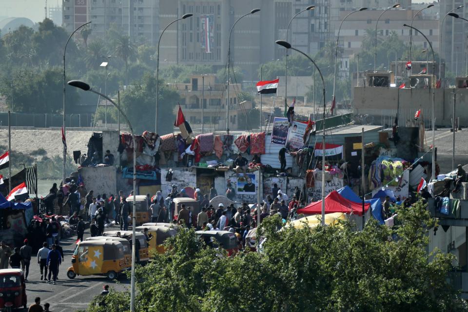 Protesters stage a sit-in at barriers on the Sinak Bridge while security forces stand guard behind concrete barriers, in Baghdad, Iraq, Thursday, Nov. 21, 2019. Renewed clashes overnight in Baghdad between anti-government demonstrators and security forces killed and wounded protesters, security and hospital officials said Thursday. (AP Photo/Hadi Mizban)