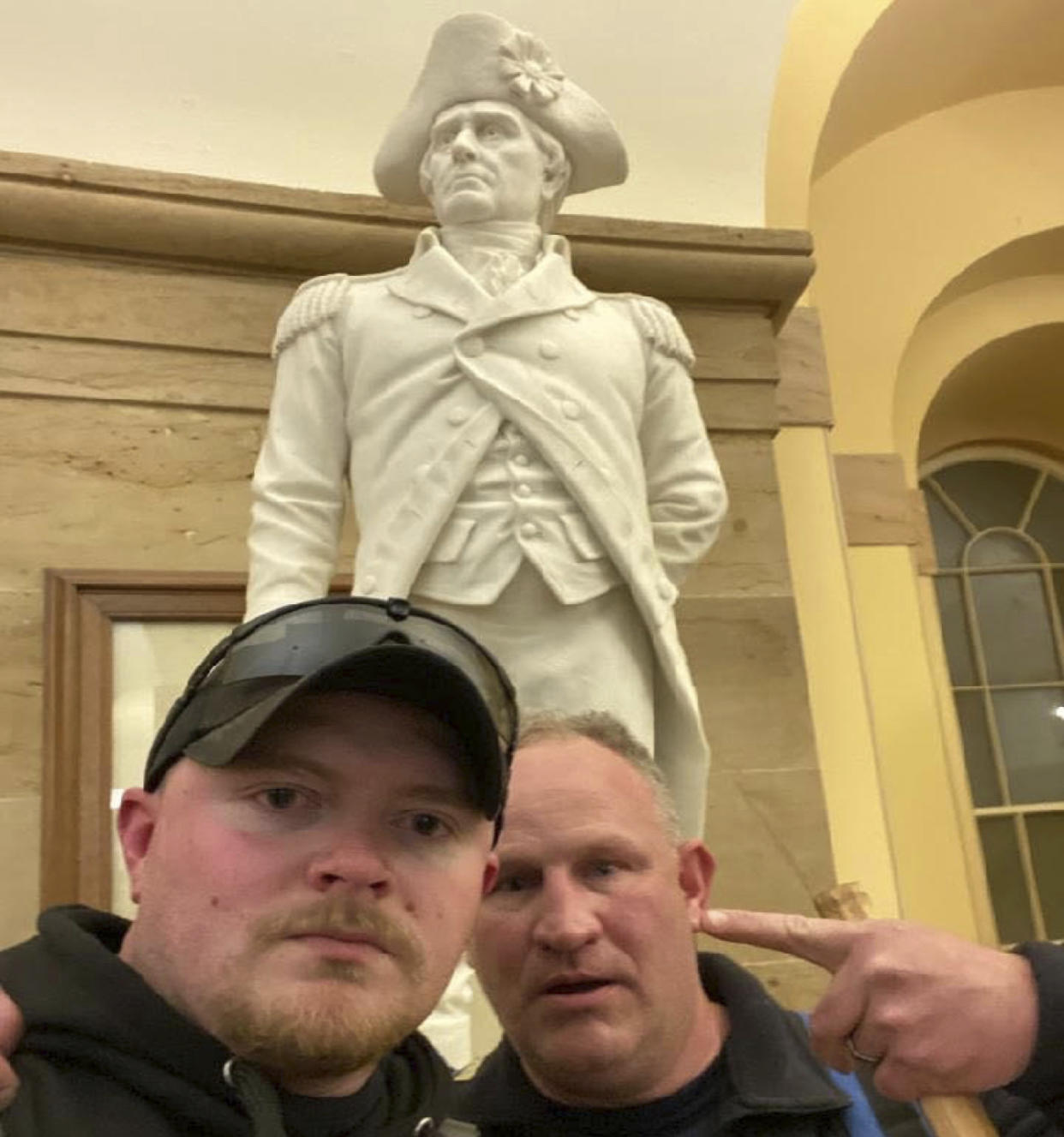 This Jan. 6, 2021 photo made available by the United States Capitol Police in a complaint and arrest warrant shows Rocky Mount Police Department Sgt. Thomas "T.J." Robertson and officer Jacob Fracker in the Capitol in front of a statute of John Stark, a Revolutionary War officer famous for writing the state motto of New Hampshire, "Live Free or Die." (Courtesy United States Capitol Police via AP)