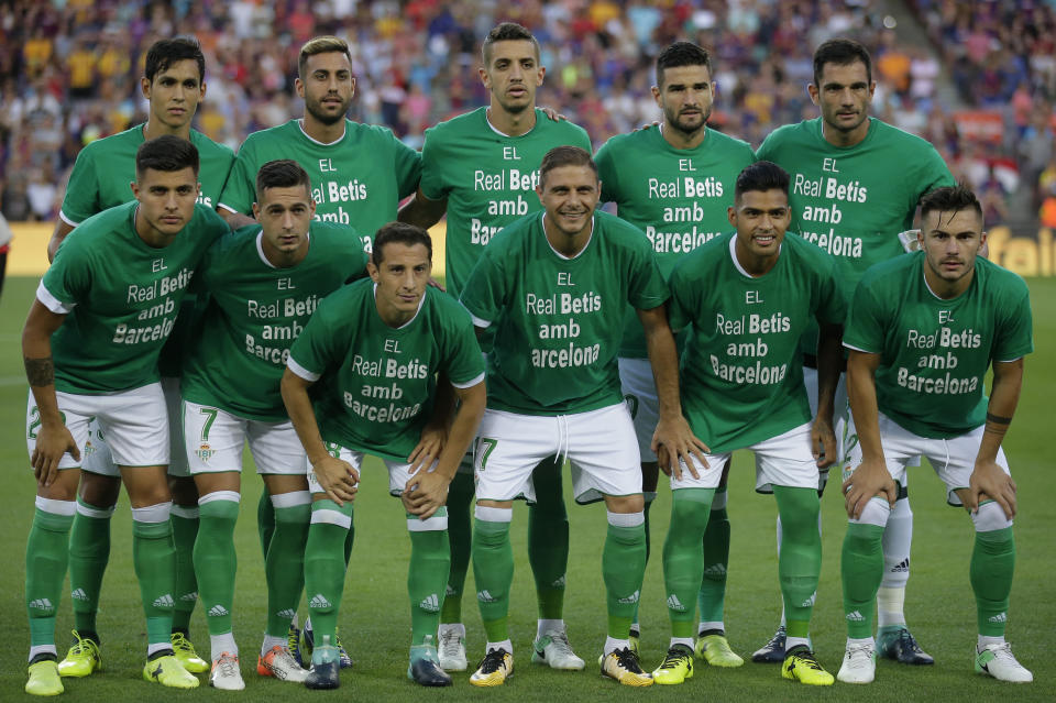 (Above) Barcelona players huddle before the match with the word “Barcelona” substituted on their jerseys in place of their names. The gesture was meant to commemorate victims of the terror attacks in the city on Thursday. (Below) Real Betis players wore shirts to honor the victims before the match began as well. (Associated Press)