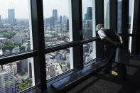 FILE - In this May 28, 2020, file photo, a visitor looks outside from Tokyo Tower, one of the town's travel spots, as it reopened the observatories in Tokyo. Japan has kept its deaths from the new coronavirus low despite a series of missteps that beg the question of whether it can prevent future waves of infections. (AP Photo/Eugene Hoshiko, File)