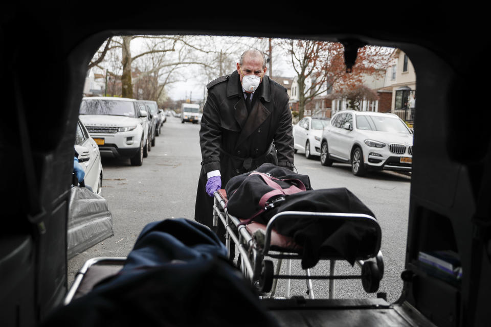 Funeral director Tom Cheeseman loads a body into his van after making a house call, Friday, April 3, 2020, in the Brooklyn borough of New York. The Associated Press spent a day on the road with Cheeseman, who is overwhelmed by demand due to the coronavirus outbreak. Cheeseman is picking up as many as 10 bodies per day. Most bodies come from homes and hospitals. “We took a sworn oath to protect the dead, this is what we do,” he said. (AP Photo/John Minchillo)