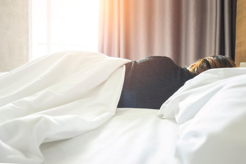 A woman sleeping on a white bed in a hotel room