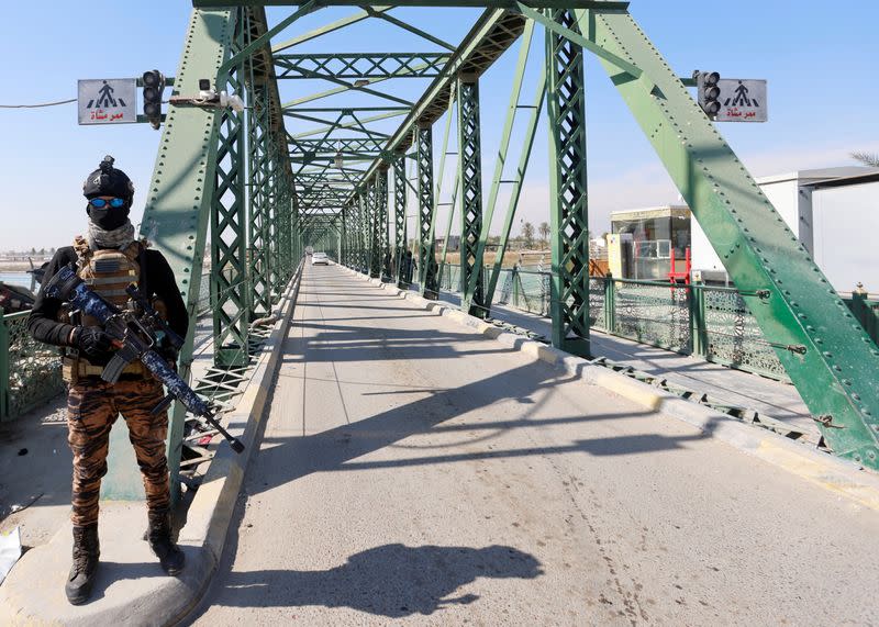 FILE PHOTO: A member of Iraqi security forces stands guard near the bridge where four contractors from U.S. security firm Blackwater were killed by Islamist groups, in Falluja