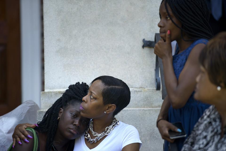 People sit on the steps of Morris Brown AME Church while services are held June 18, 2015 in Charleston, South Carolina. Police on Thursday arrested a 21-year-old white gunman suspected of killing nine people at a prayer meeting in one of the nation's oldest black churches in Charleston, an attack being probed as a hate crime. The shooting at the Emanuel African Methodist Episcopal Church in the southeastern US city was one of the worst attacks on a place of worship in the country in recent years, and comes at a time of lingering racial tensions. 