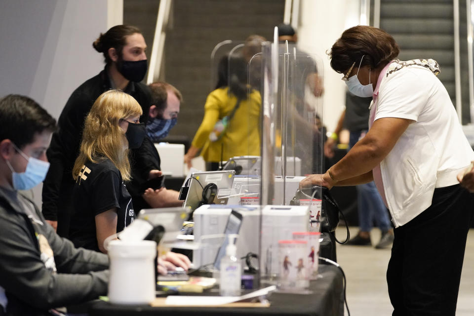 People register before voting early at the State Farm Arena on Monday, Oct. 12, 2020, in Atlanta. (AP Photo/Brynn Anderson)