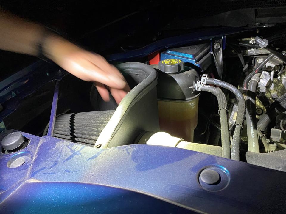 In California, an Oxnard police officer points out an illegal air intake system under the hood of a modified truck pulled over during a 2020 traffic enforcement operation targeting street racing, stunt driving and modified vehicles.