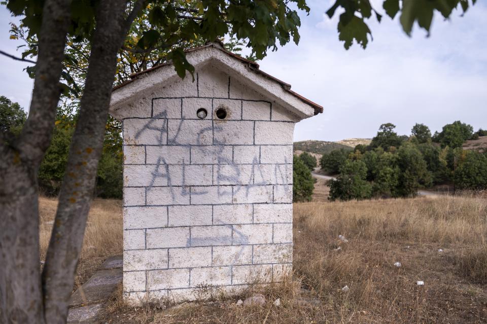 A makeshift sign on a Greek Orthodox chapel shows the way to Albania, near Ieropigi village, northern Greece, at the Greek - Albanian border, on Tuesday, Sept. 28, 2021. A relatively smooth section of Greece's rugged border with Albania is turning into a major thoroughfare north for migrants in Greece seeking a better life in Europe's prosperous heartland. (AP Photo/Giannis Papanikos)