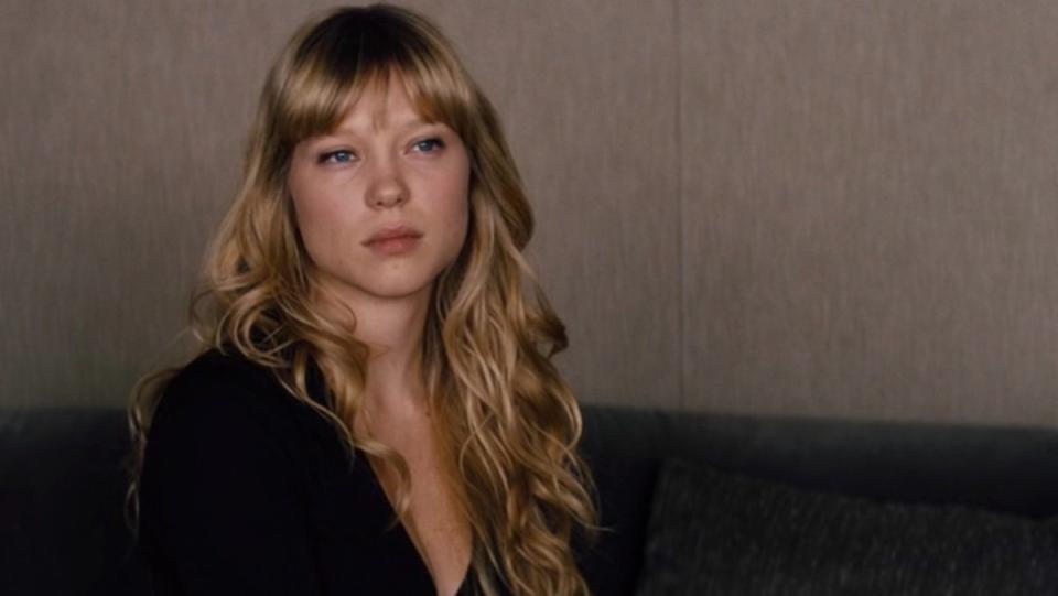 A blonde woman in a black dress on a couch in Mission: Impossible - Ghost Protocol