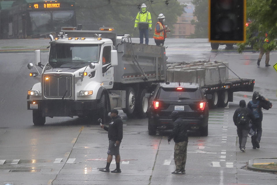 A truck is loaded with concrete barricades after Seattle Department of Transportation workers removed them at the intersection of 10th Ave. and Pine St., Tuesday, June 30, 2020 at the CHOP (Capitol Hill Occupied Protest) zone in Seattle. Protesters quickly moved couches, trash cans and other materials in to replace the cleared barricades. The area has been occupied by protesters since Seattle Police pulled back from their East Precinct building following violent clashes with demonstrators earlier in the month. (AP Photo/Ted S. Warren)