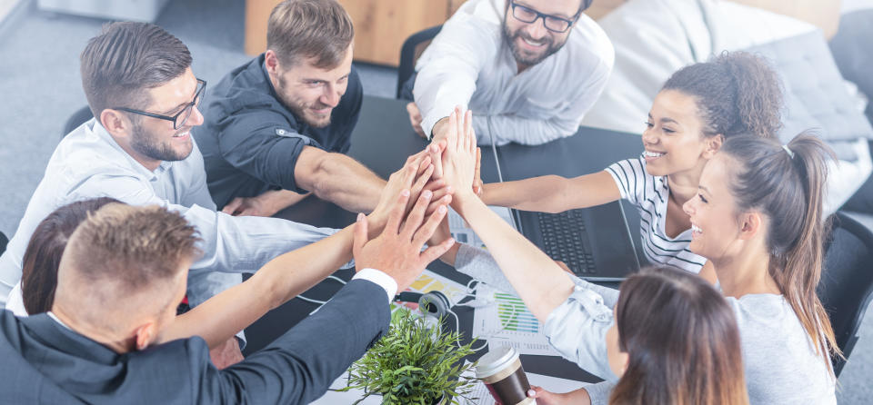 Group of young adults in a circle high-fiving