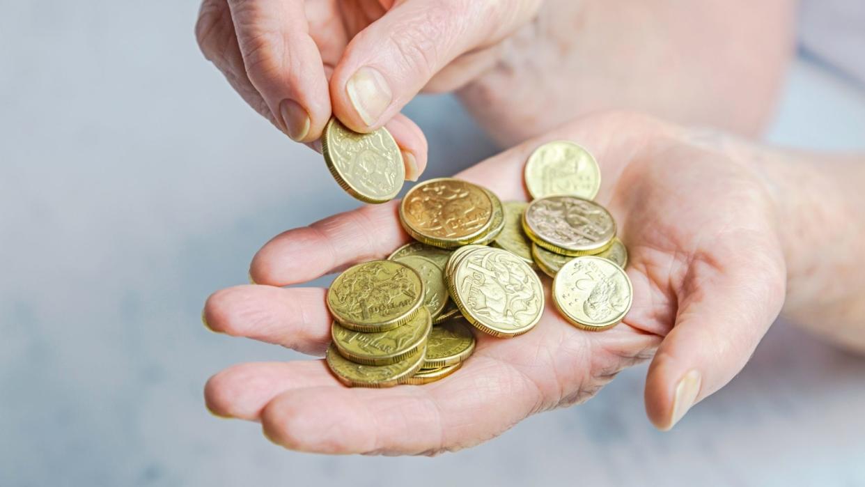 Hands holding gold Australian coins. 