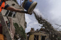 A worker cleans debris from a rocket strike on a house in Kramatorsk, Donetsk region, eastern Ukraine, Friday, Aug. 12, 2022. There were no injuries reported in the strike. (AP Photo/David Goldman)