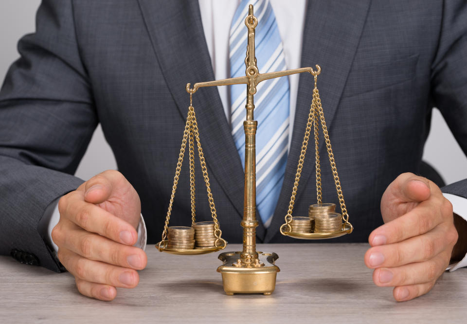 Man in suit weighing gold coins using a traditional balance scale