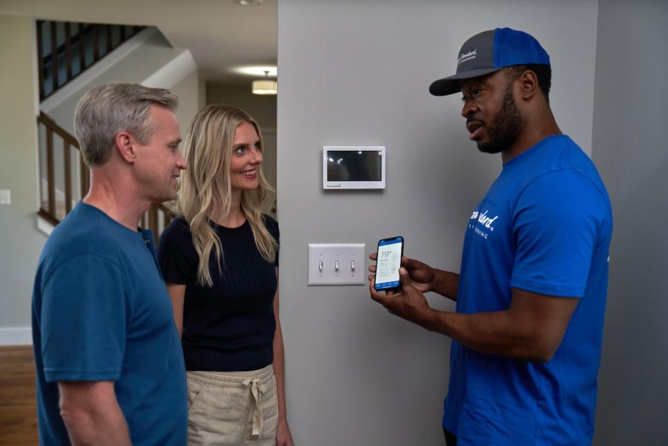 An American Standard HVAC professional speaking with homeowners about their new heat pump and tax breaks.