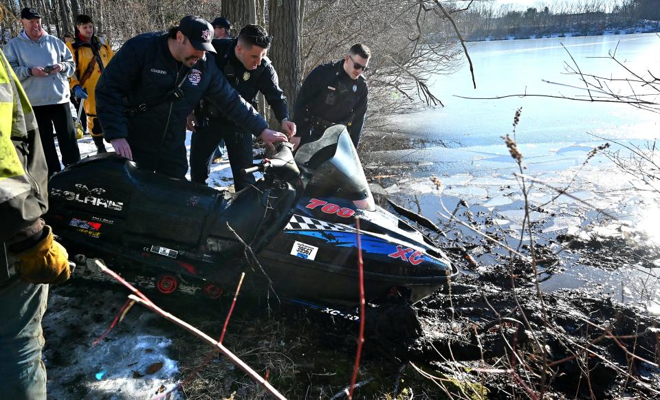Shrewsbury police search for a VIN number on a snowmobile that had broken through the ice along with its driver at Jordan Pond Tuesday afternoon.