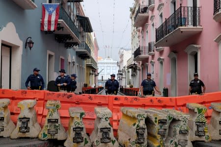 Police officers stand guard by a barricade on a street that leads to La Fortaleza, the official residence of the Governor of Puerto Rico, in Old San Juan