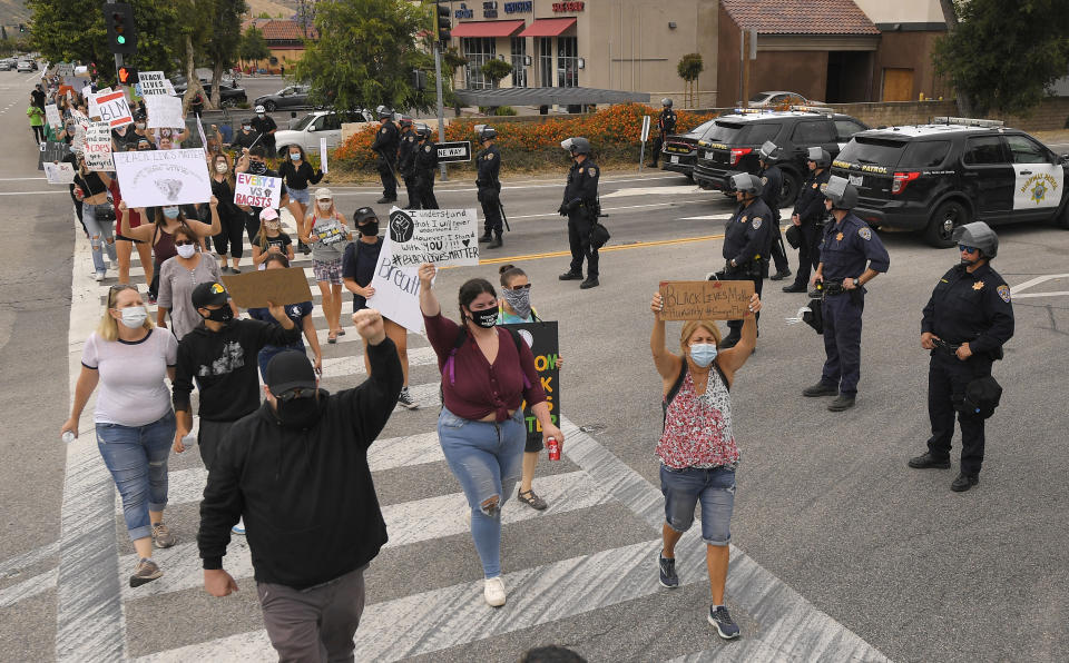 Demonstrators walks in front of California Highway Patrol officers that are blocking the entrance to the freeway during a protest, Saturday, June 6, 2020, in Simi Valley, Calif., over the death of George Floyd. Floyd died after he was restrained in police custody on Memorial Day in Minneapolis. (AP Photo/Mark J. Terrill)