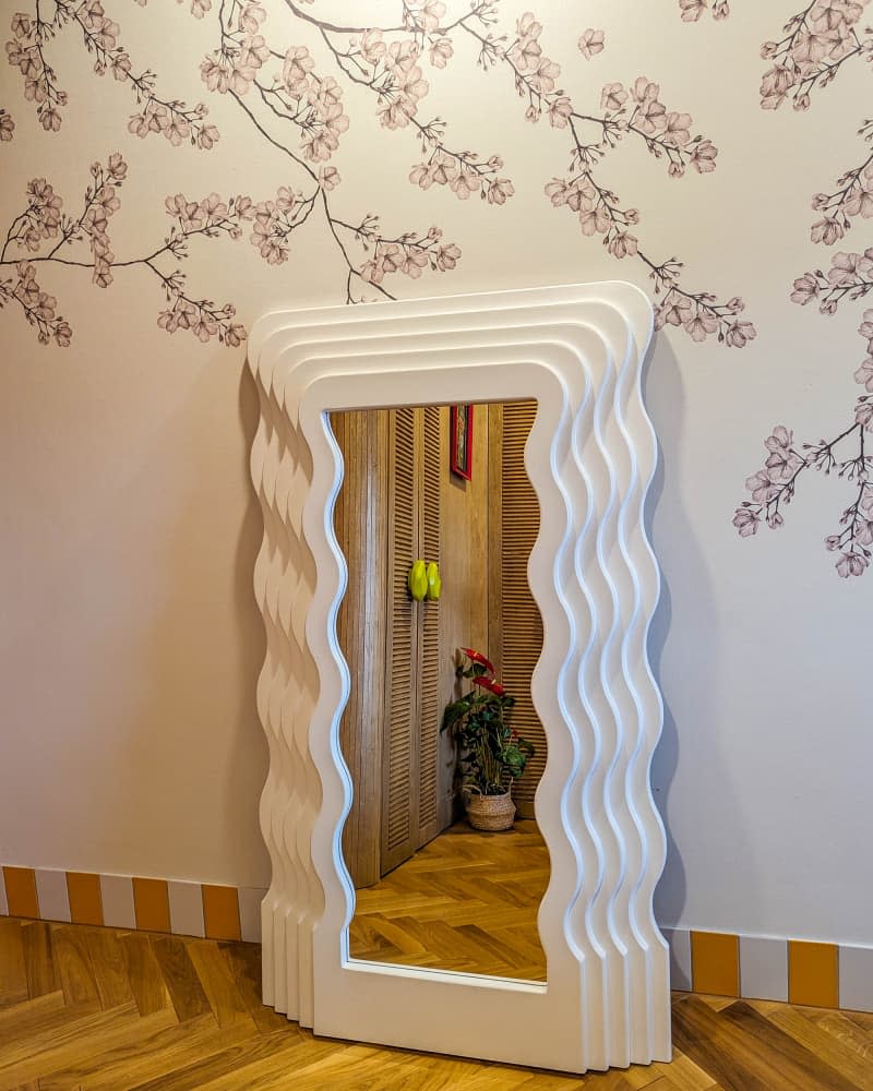 detail of white wavy mirror on bedroom floor