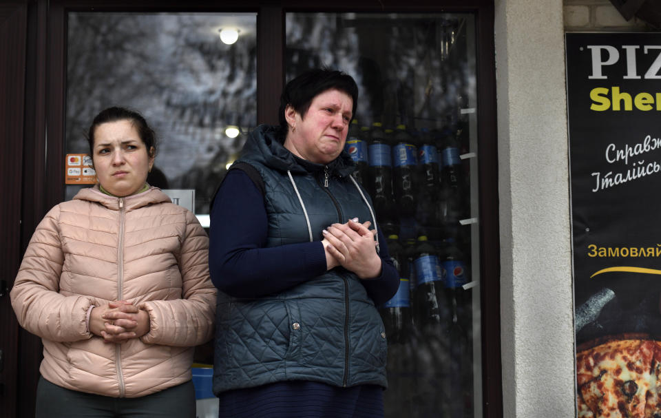 Two residents watch as a procession of mourners passes by.