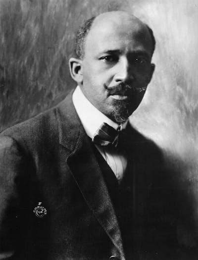 A Black man dressed in a dark suit and wearing a bow tie poses for a portrait.