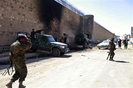 Policemen stand guard next to a wall of the central prison in Sanaa after a bomb exploded outside, February 14, 2014. REUTERS/Mohamed al-Sayaghi