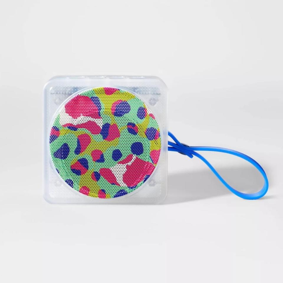 Round, multicolored patterned bag with a blue strap against a white background