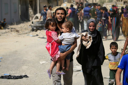 A displaced Iraqi man who fled from clashes, carries children in western Mosul, Iraq, June 3, 2017. REUTERS/Alaa Al-Marjani