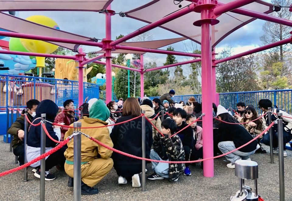 Visitors crouch under a pink structure as an earthquake hit the region at Universal Studios Japan in Osaka in 2024