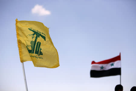 FILE PHOTO: Hezbollah and Syrian flags are seen fluttering in Fleita, Syria August 2, 2017. REUTERS/ Omar Sanadiki/File Photo