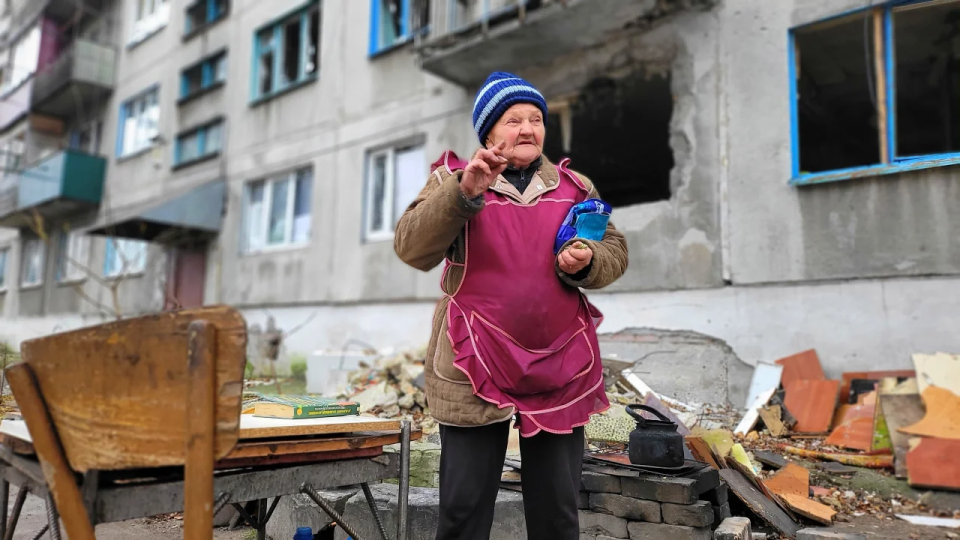 A resident of Lyman prepares lunch in an improvised kitchen right on the street <span class="copyright">NV</span>