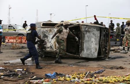 A soldier and a paramilitary officer help to move part of a damaged car at the scene of a car bomb attack in Nyanya, Abuja, May 2, 2014. REUTERS/Afolabi Sotunde