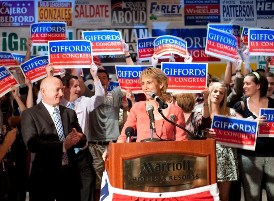 Gabrielle Giffords speaks on election night at Democratic Election Headquarters as her husband Mark Kelly applauds.