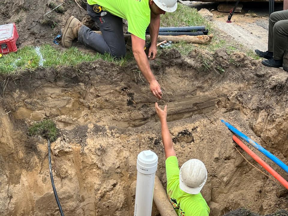 Crew members exchange parts during a lead service line replacement on Wednesday, July 5, 2023, in Grand Rapids, Mich.