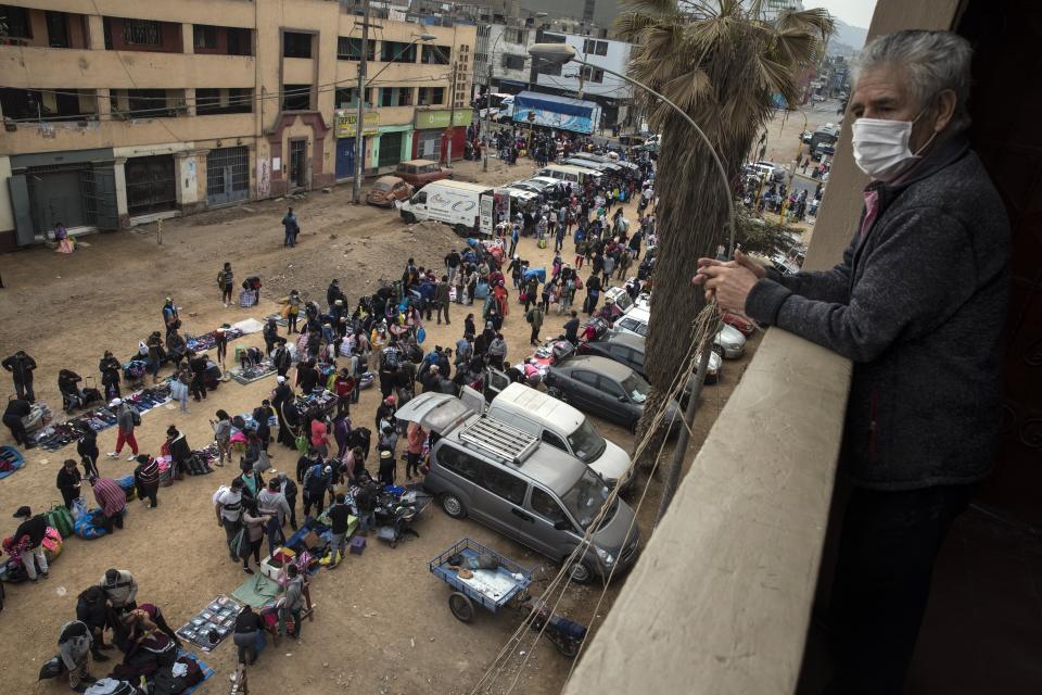 A resident watches as street vendors ignore lockdown measures to curb the spread of the new coronavirus, and sell their products in La Victoria district, in Lima, Peru, Tuesday, June 16, 2020. (AP Photo/Rodrigo Abd)