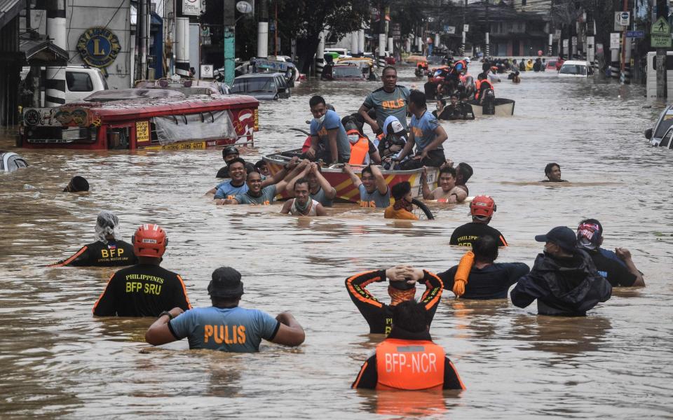 Rescuers pull a rubber boat carrying residents through a flooded street  - AFP