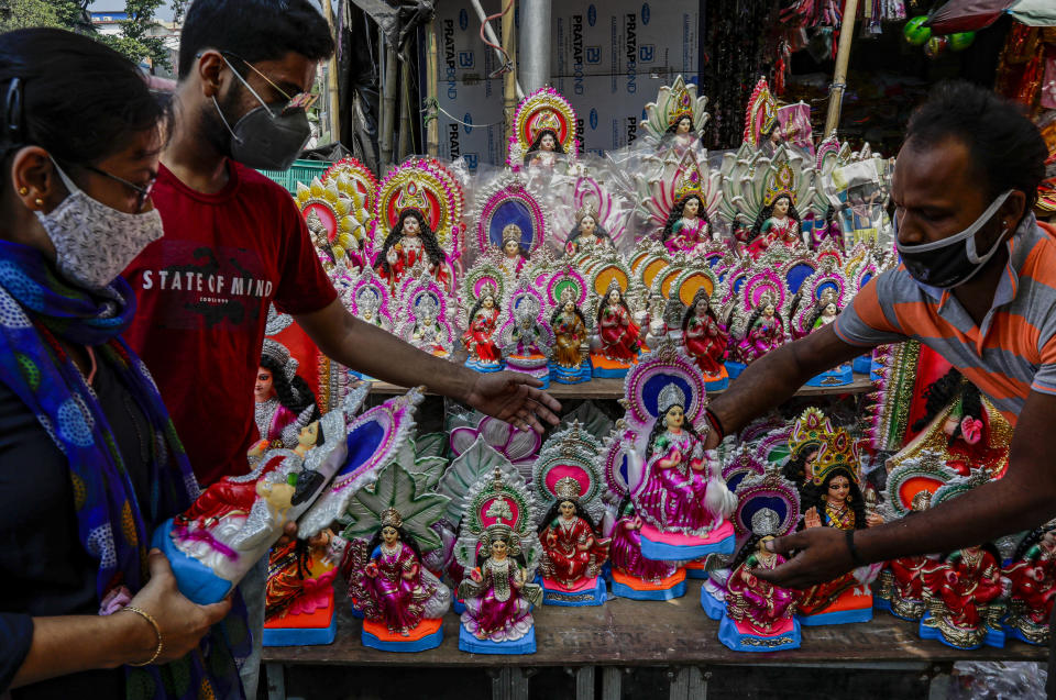 People buy clay idols of Laxmi, the Hindu goddess of wealth, ahead of Laxmi Puja festival in Kolkata, India, Thursday, Oct. 29, 2020. India's confirmed coronavirus caseload surpassed 8 million on Thursday with daily infections dipping to the lowest level this week, as concerns grew over a major Hindu festival season and winter setting in. (AP Photo/Bikas Das)