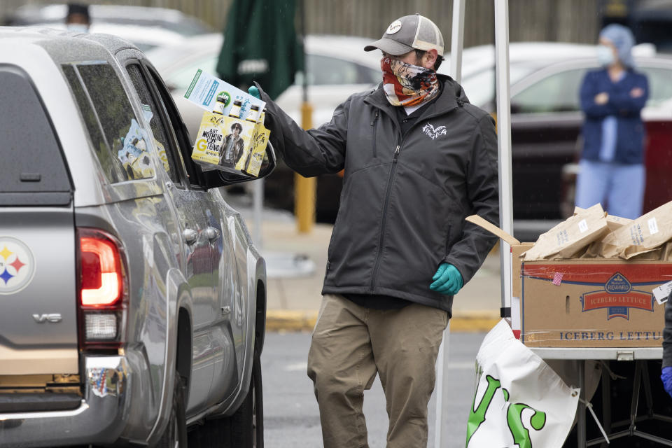 Flying Dog Brewery employee CJ Winpigler gathers beer and food to distribute during an event with businesses including Flying Dog Brewery, Roast House Pub, McCutcheons and Frederick Balloons to front line essential workers, including healthcare and first responders in Frederick, Md., Tuesday, April 28, 2020. (AP Photo/Jon Elswick)