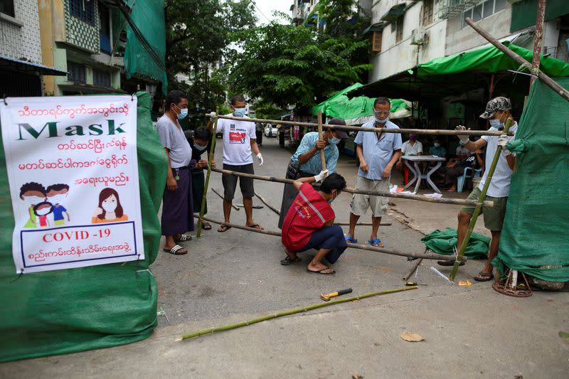 Men construct a barricade blocking off their street to prevent the spread of the coronavirus disease in Yangon