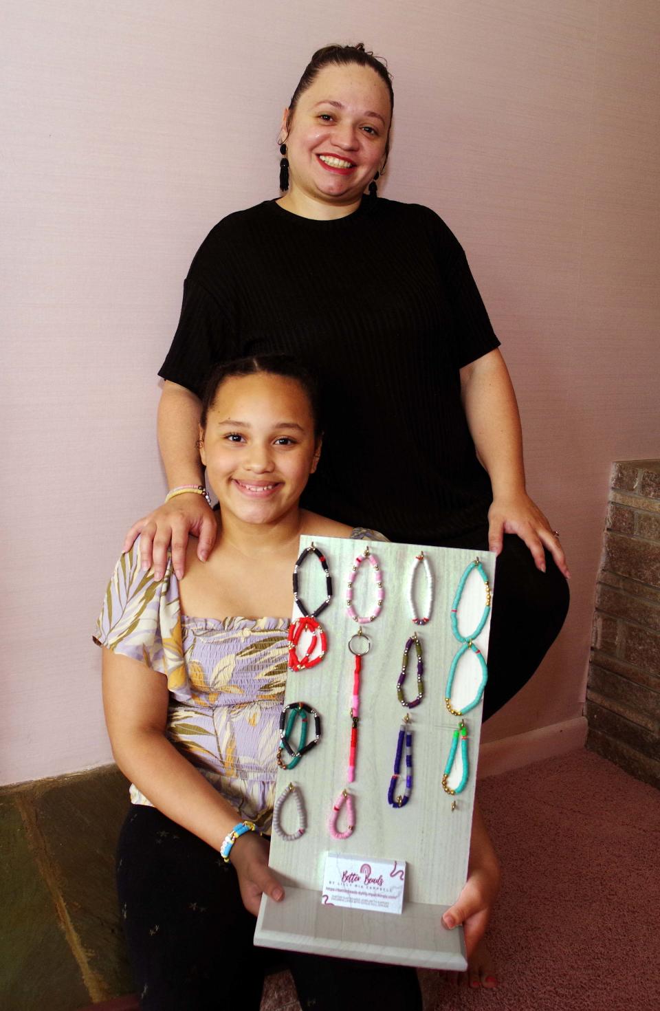 Lilly Campbell, 9, of Brockton, and founder/owner of Better Beads which works to bring awareness to individuals with sickle cell anemia stands with her mother Diamyr "Mimi" Campbell, who serves as her advisor and biggest fan while showing her finished bracelet work at their home on Thursday, May 25, 2023.