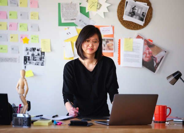 Asian woman working on room with post-its on the wall 