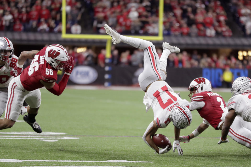 Ohio State wide receiver Chris Olave (17) is tackled by Wisconsin safety Reggie Pearson (2) as linebacker Zack Baun (56) watches during the second half of the Big Ten championship NCAA college football game Saturday, Dec. 7, 2019, in Indianapolis. (AP Photo/Michael Conroy)