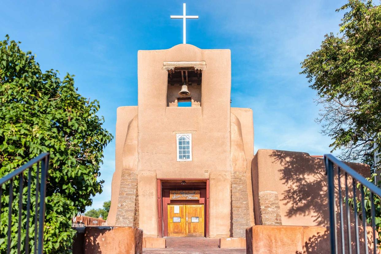 San Miguel Mission chapel oldest church in the United States with adobe pueblan style architecture, blue cross and blue sky